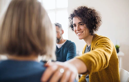 A woman smiling and talking with others during a supportive group conversation.