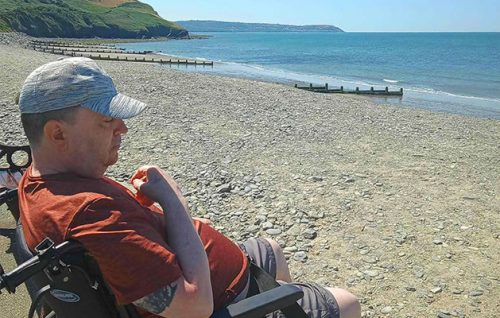 A client enjoying the view over the beach and seascape during a supported holiday with Headway Shropshire