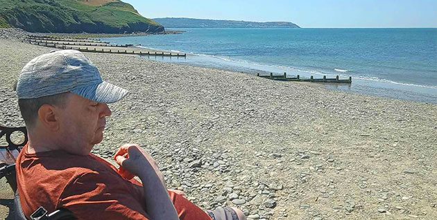 A client enjoying the view over the beach and seascape during a supported holiday with Headway Shropshire