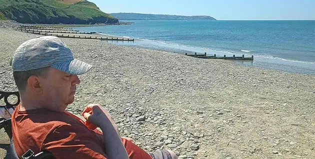 A client enjoying the view over the beach and seascape during a supported holiday with Headway Shropshire
