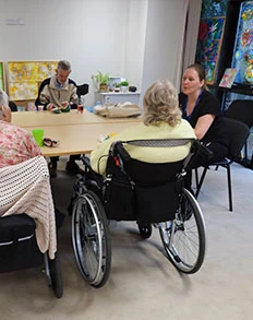 People seated around a table during a group activity at Headway Shropshire, including two wheelchair users.